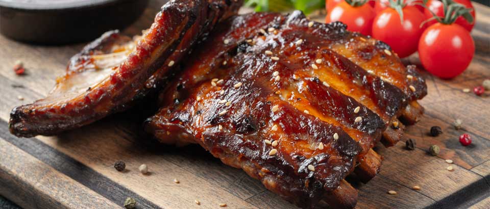 bbq ribs on wood cutting board with tomatoes