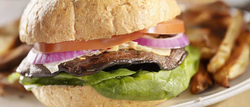 portobello mushroom burger with lettuce, tomato and onion on plate