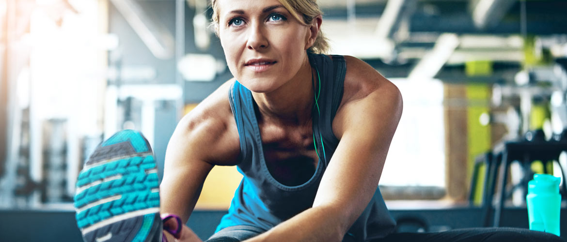 woman sit stretching over one leg at gym