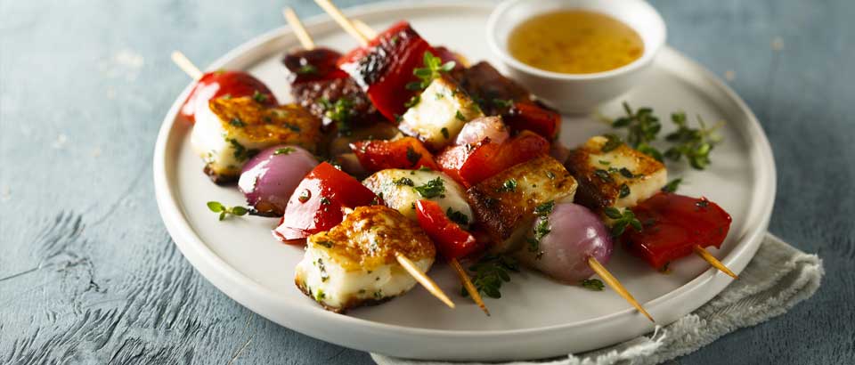  tofu, onion and pepppers on skewers on plate with dipping sauce