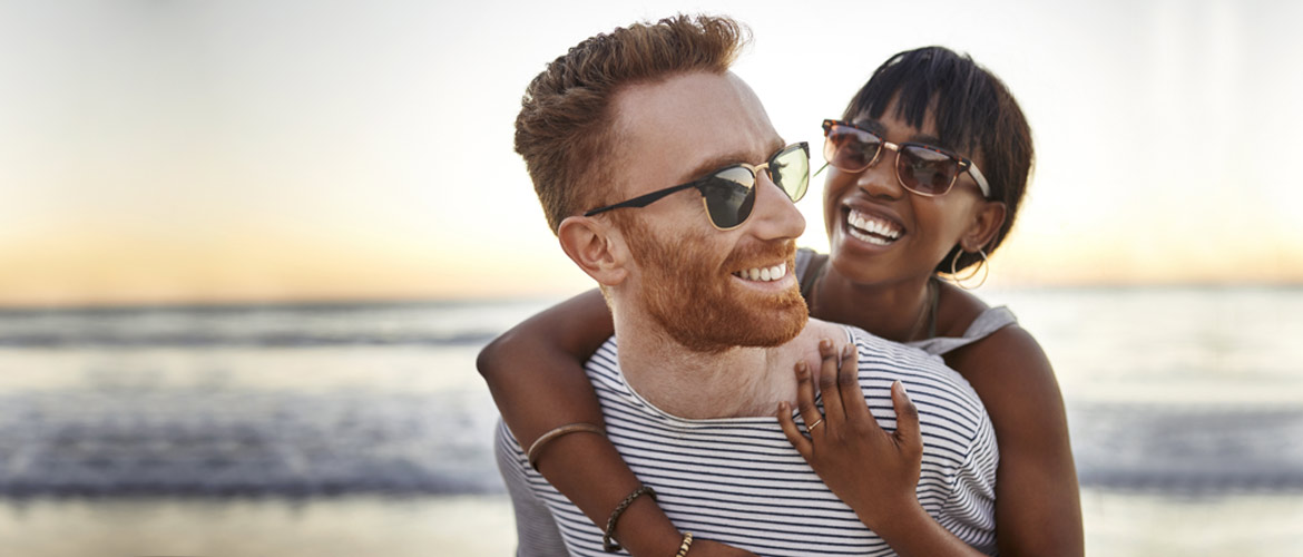 woman hugging male partner from behind on the beach