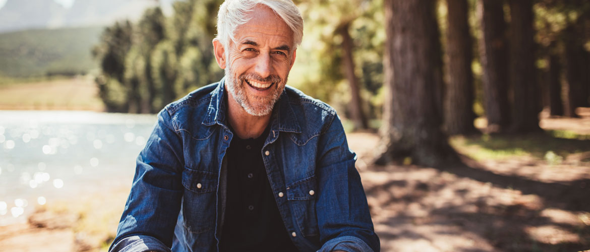 closeup of a man smiling outdoors by a lake