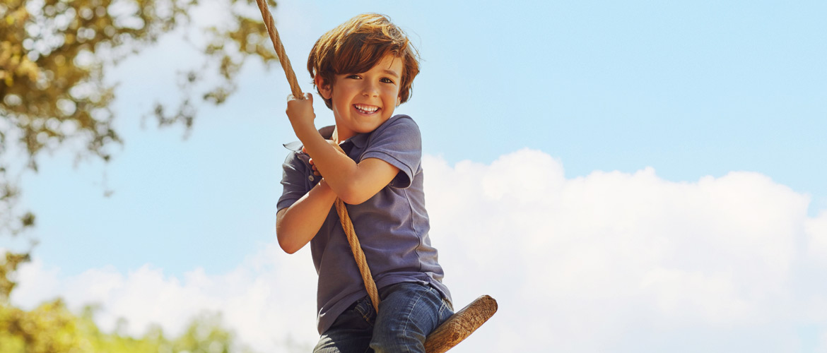 kid on tire swing smiling