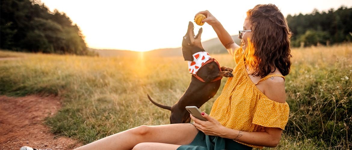 young woman in field plays with her small dog