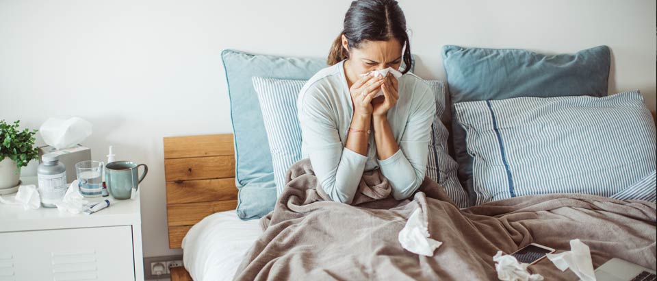 woman sitting in bed blowing nose