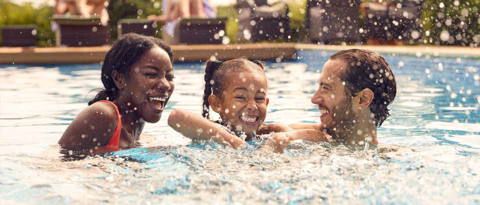 children playing in swimming pool with father