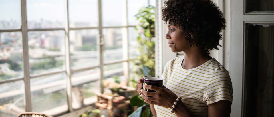 woman holding coffee and looking out a window