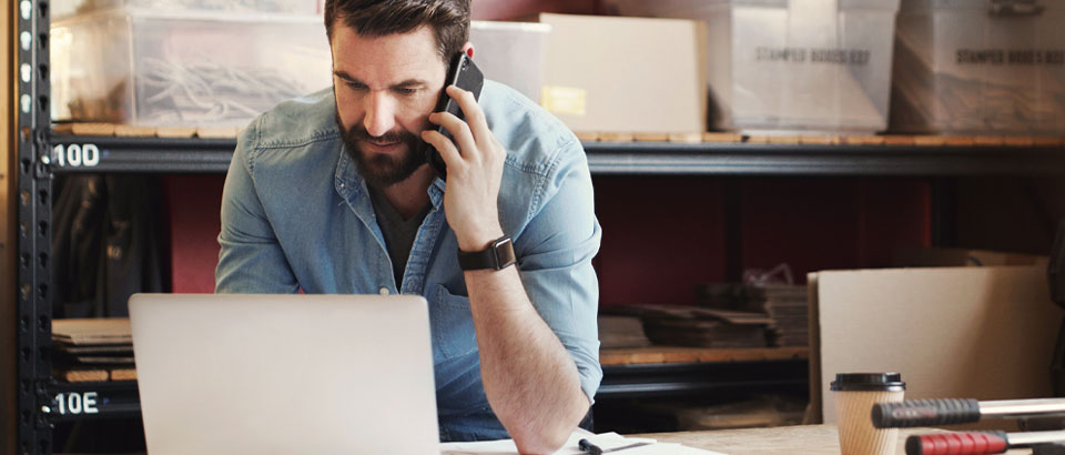 man talking at phone on laptop