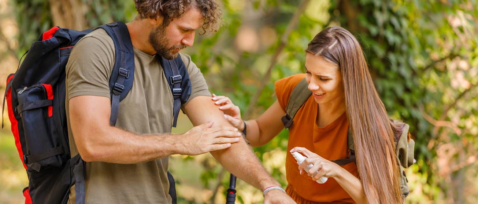 two people applying bug spray