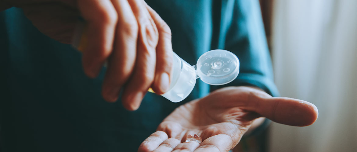 person using travel bottle of hand sanitizer