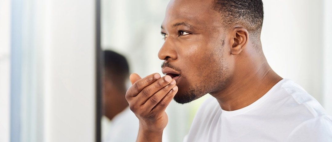 a man breathing into his hand to check the smell of his breath