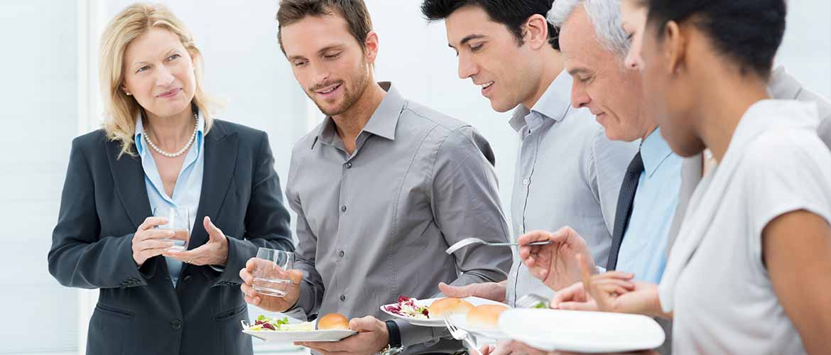 a group of employees holding plates of food and drinks