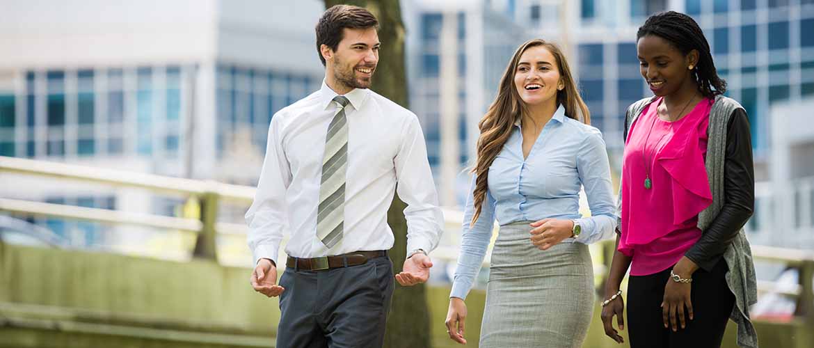 a man and two women dressed in business attire walking outside