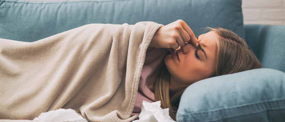 woman holding her nose while laying on the couch