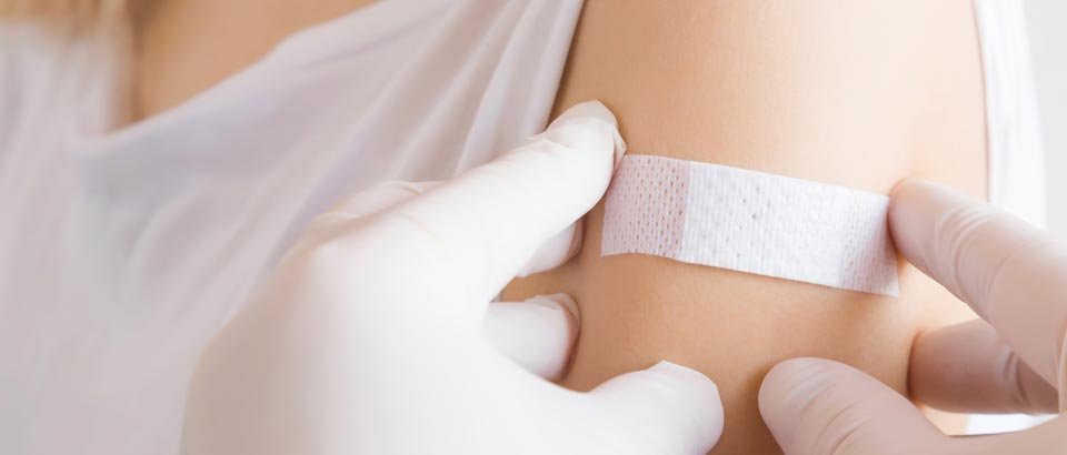 closeup of a person putting a bandage on another person's arm