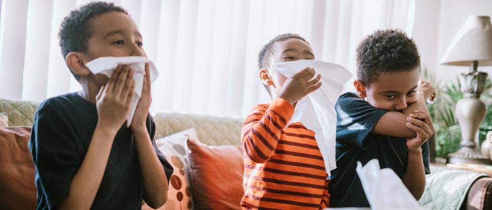 three little boys using tissues to wipe their noses