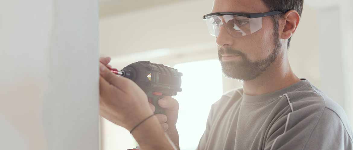 a man wearing goggles to protect his eyes while using a power drill