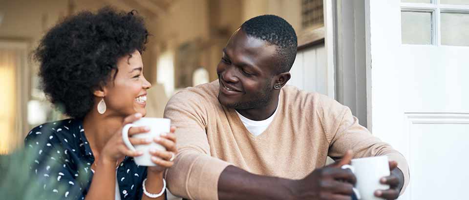 a man and woman sitting in a kitchen enjoying a cup of coffee