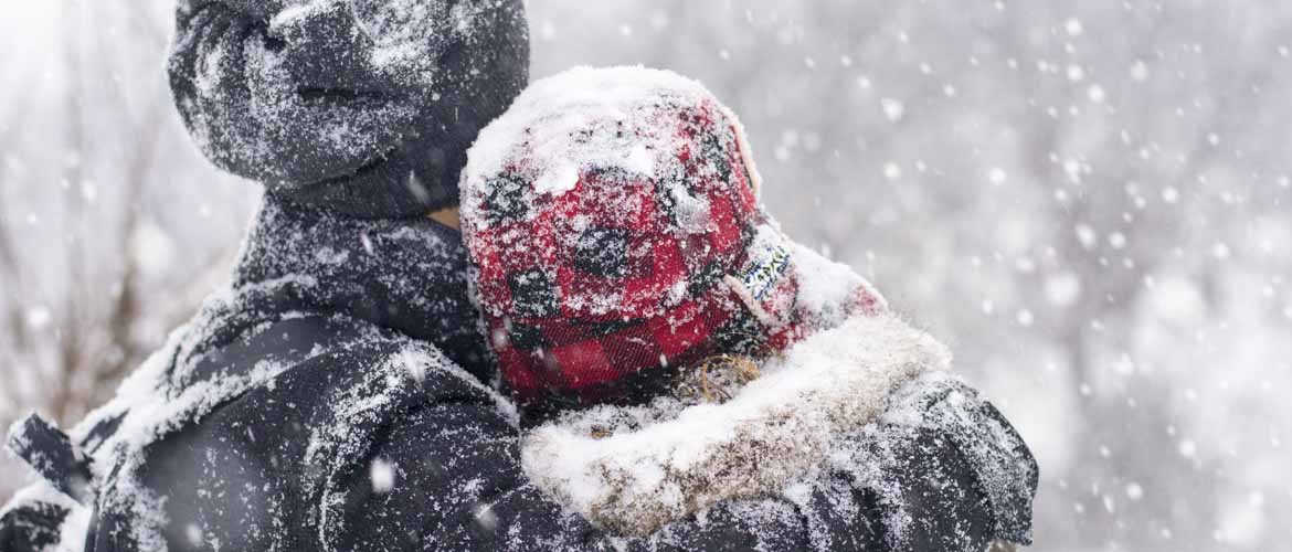 a man and a woman standing outside while it's snowing