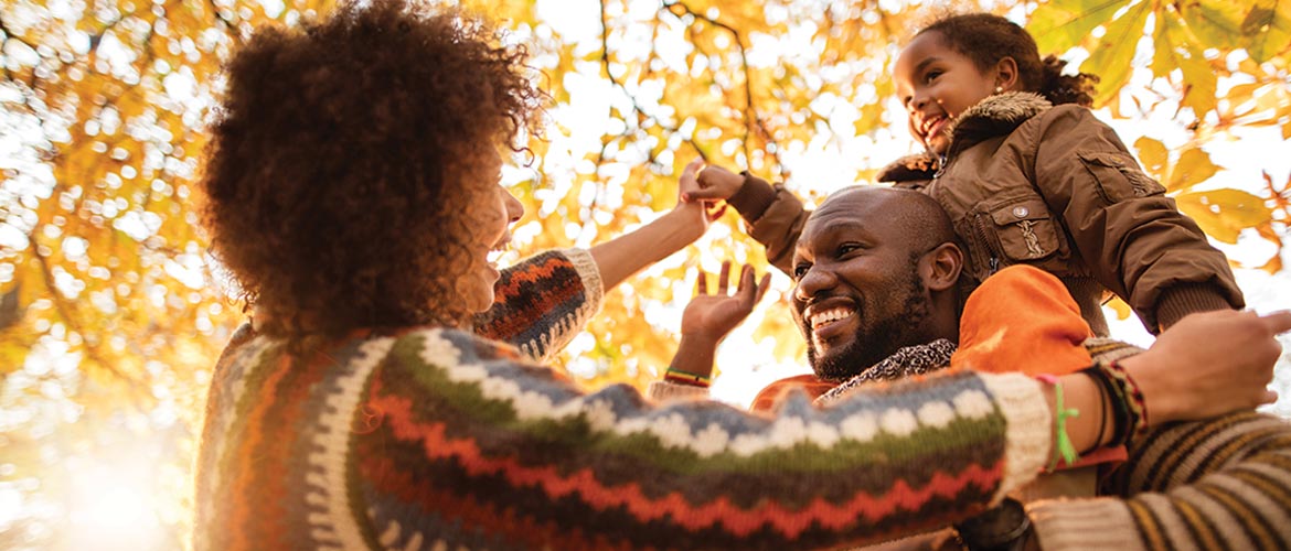 Father, mother and child outdoors among the fall leaves playing and laughing