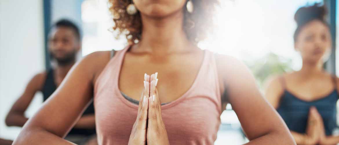 two women and a man practicing meditation at a yoga studio