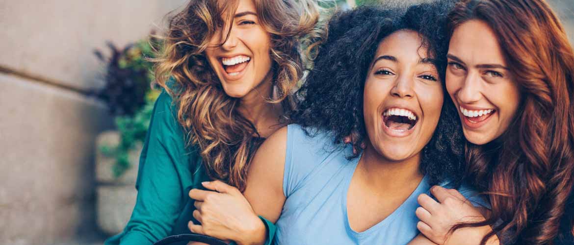 group of three girls holding on to each other and smiling