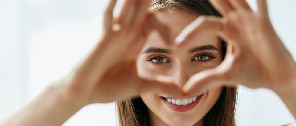 woman holding up her hands in the shape of a heart