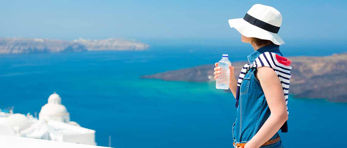 a woman overlooking a city and the ocean while drinking from a bottle of water