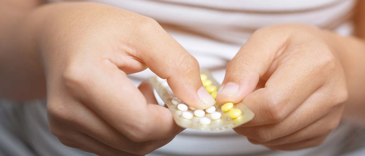 a woman holding a package of contraceptive pills