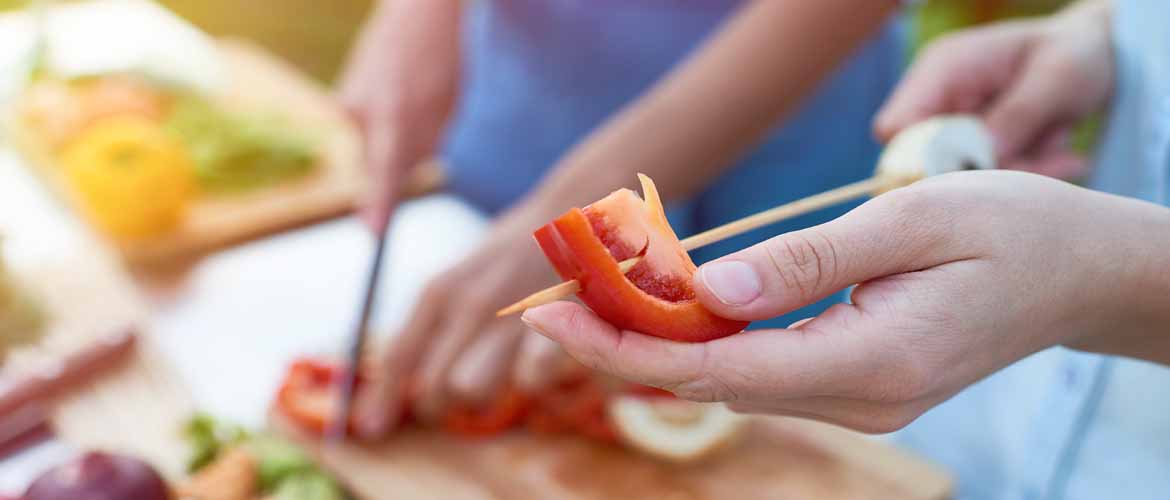 two people preparing vegetables for shish kabobs