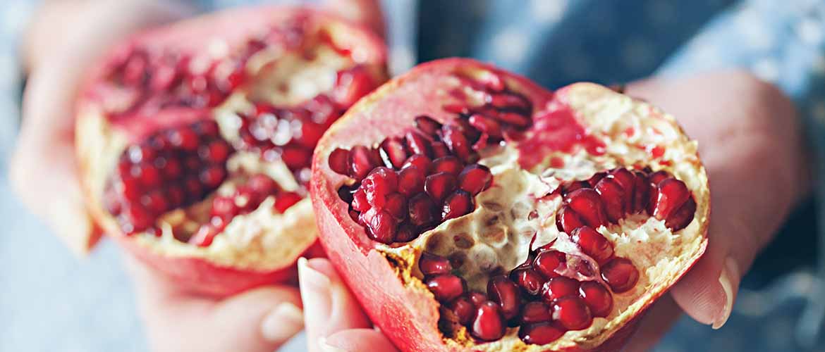 a person holding a pomegranate that's cut in half