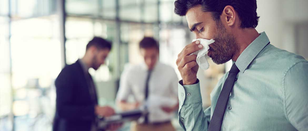 A man at work blowing his nose