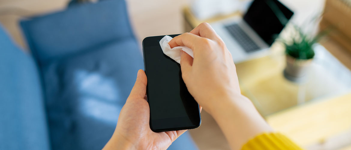 person cleaning smartphone with antibacterial wipe