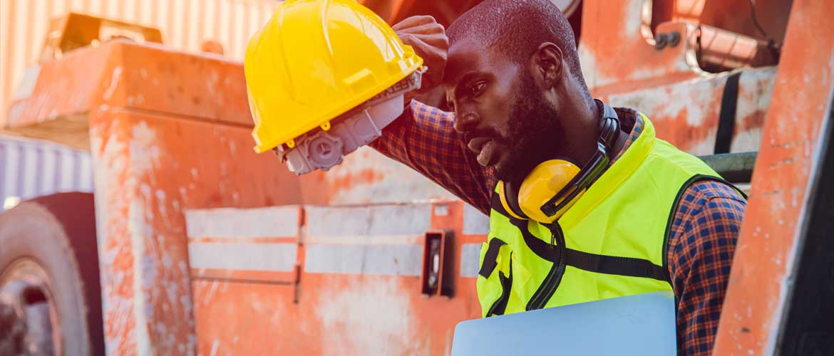 man with hard hat wiping sweat from brow