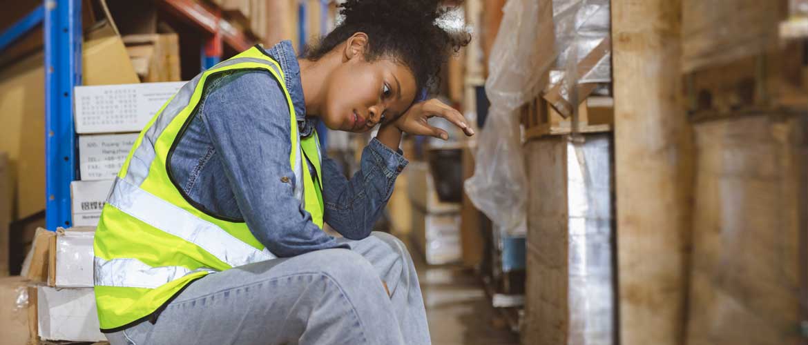 women sitting in warehouse with hand on head